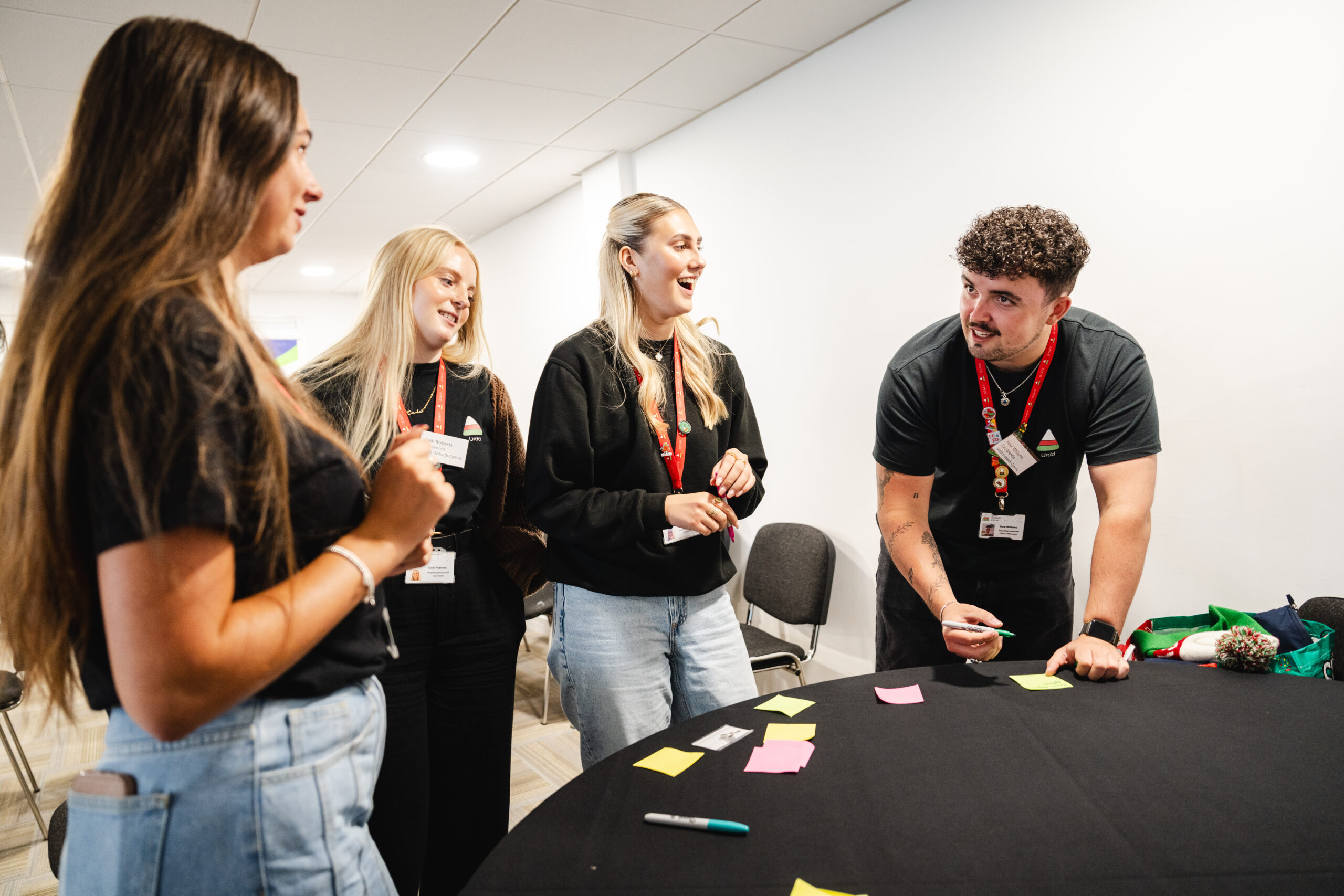 A group of apprentices laughing while doing an activity around a table