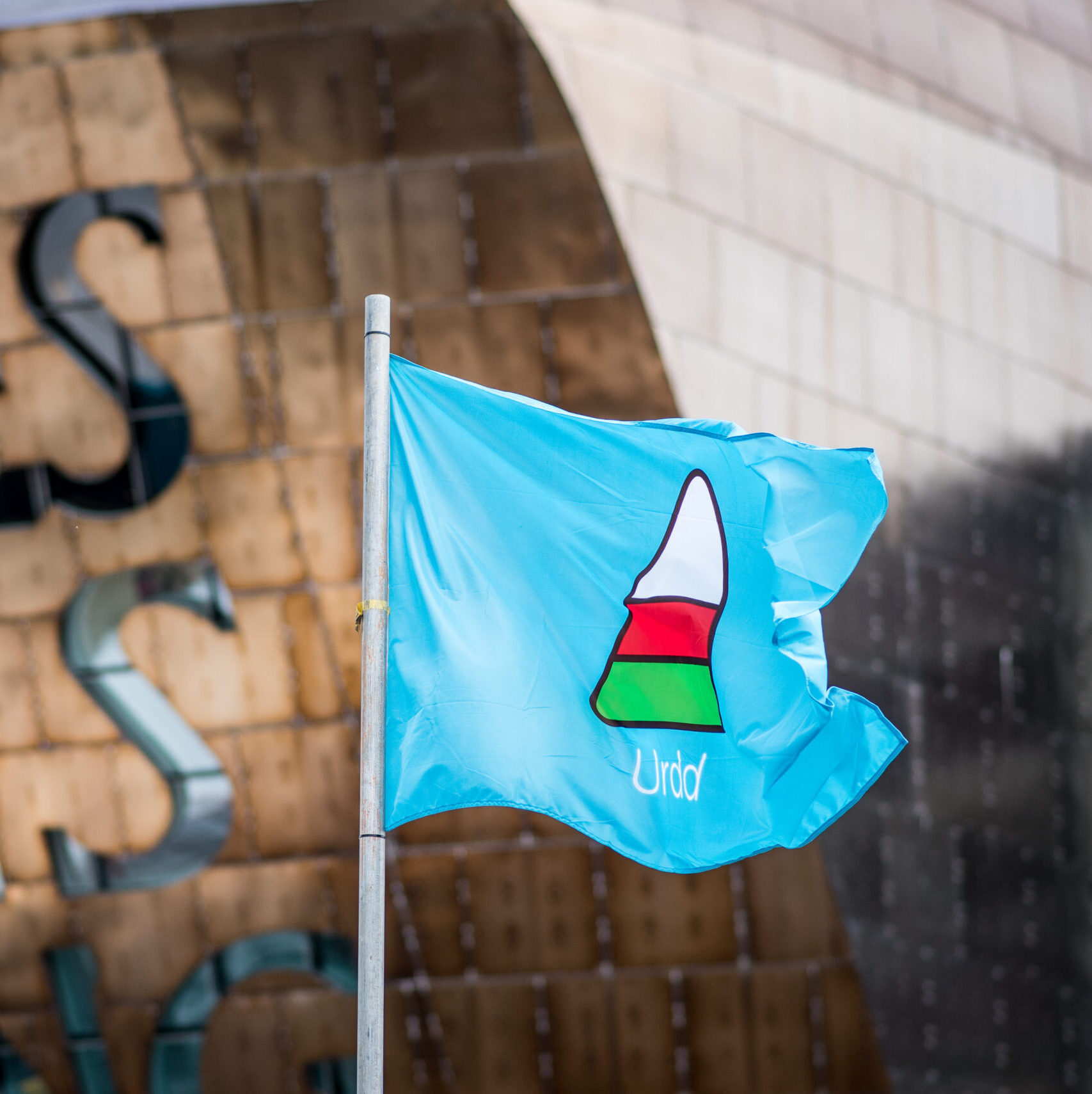 Blue Urdd flag in front of the Wales Millennium Centre