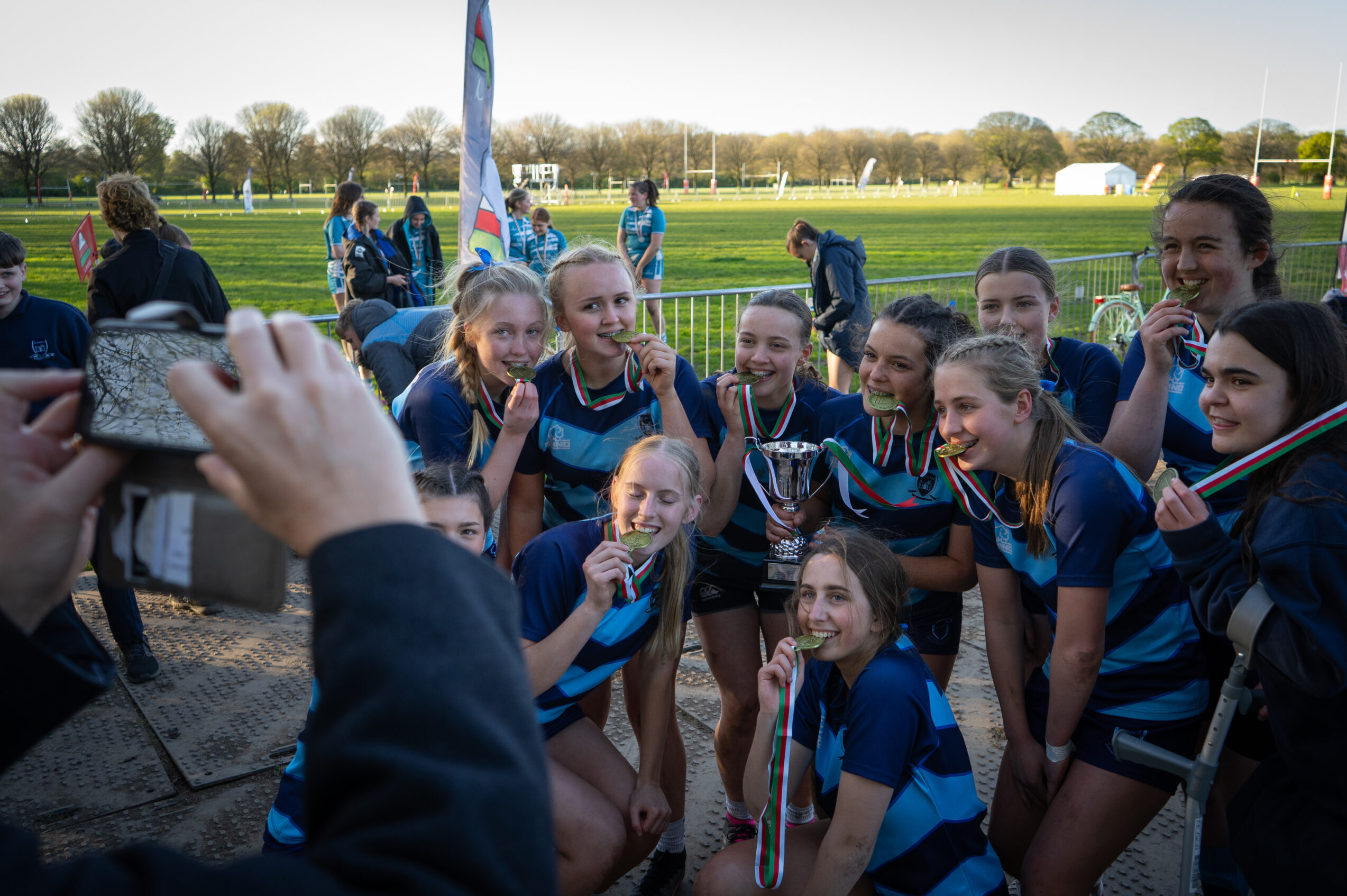 Rugby 7s girls team taking a picture with their trophy and medals after winning the tournament