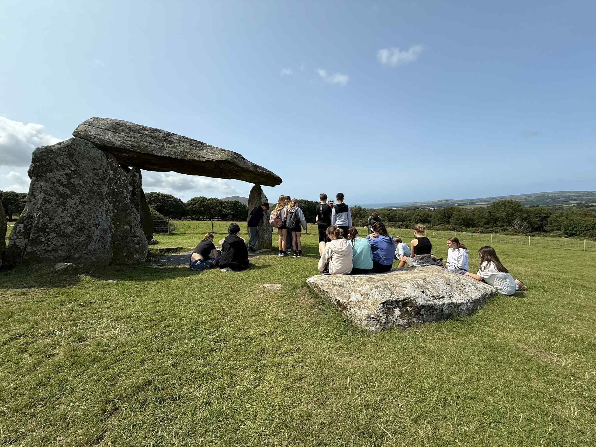 Grwp o blant yn mwynhau ymweld a Pentre Ifan ar ddiwrnod braf